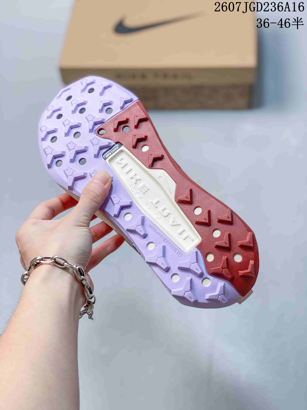 Close view of the multicolor lugged outsole with red and lavender traction sections and open channels.