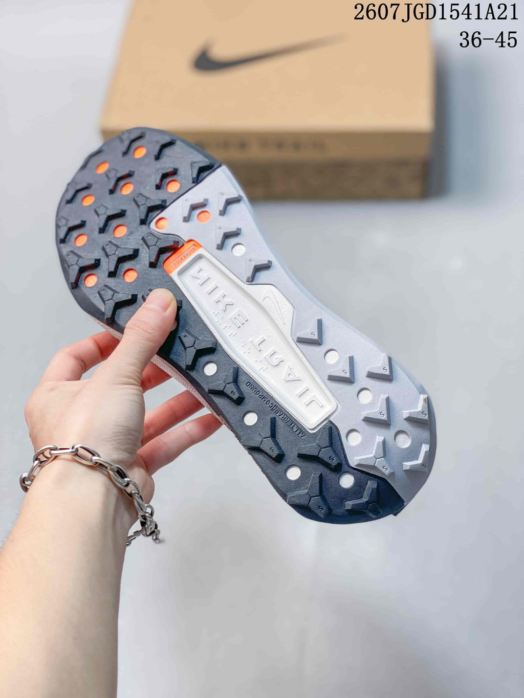 Underside view of the sneaker showing a lugged outsole with dark and light tread sections and circular openings.