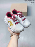 Pair of white On kids' running shoes with burgundy laces, burgundy collar lining, and yellow side branding, shown from above.