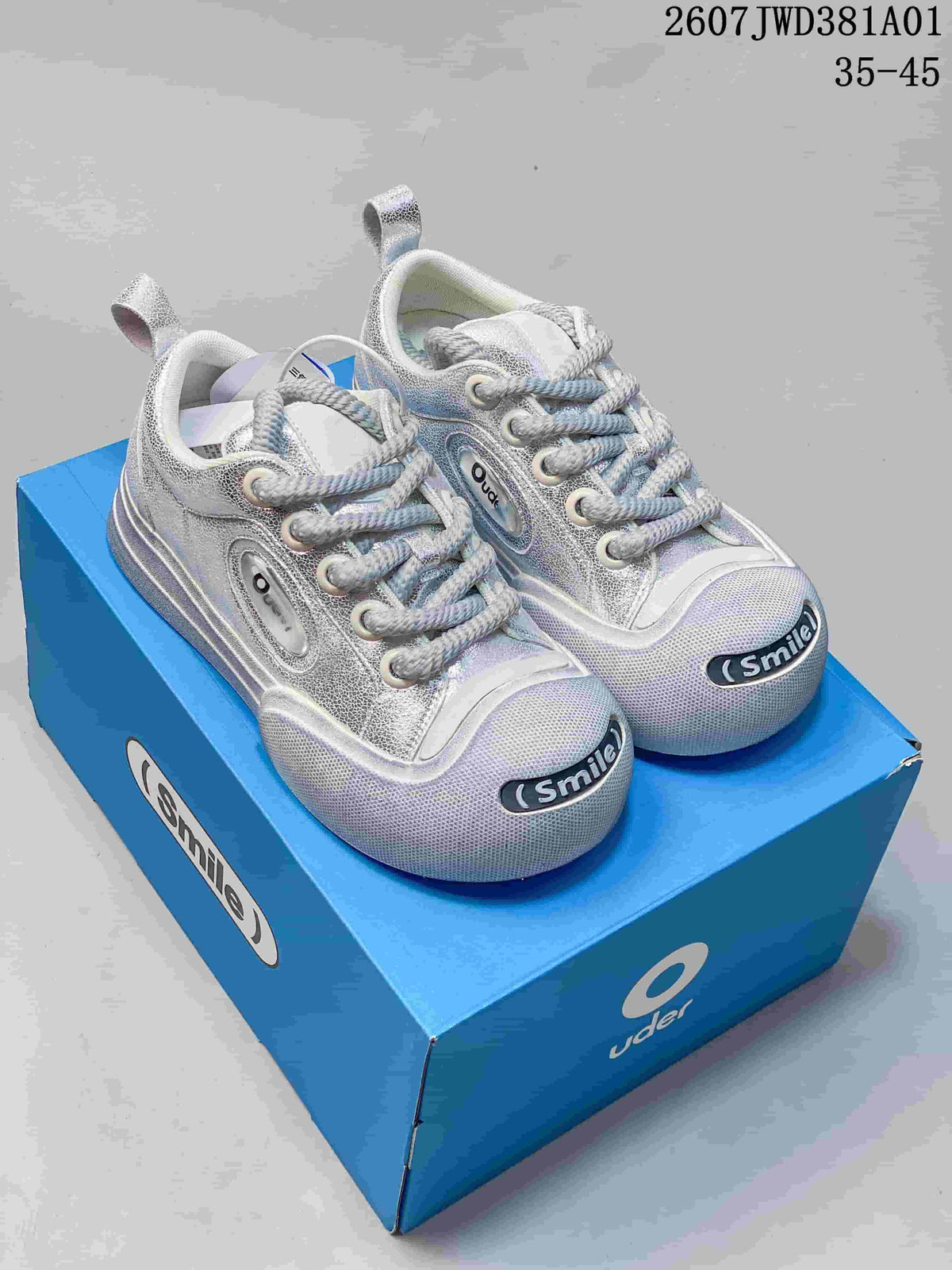 Silver Ouder chunky lace-up sneakers with rounded Smile toe detail on a blue box.