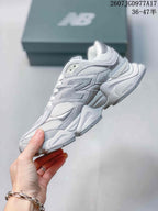 Side profile of the gray New Balance 9060 sneaker showing layered panels, mesh sections, and a chunky outsole.