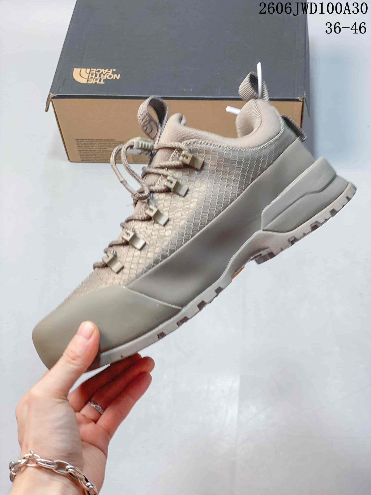 Side view of a taupe low-top shoe with patterned upper and protective overlays