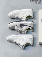 Three low-top sneakers shown from the side, illustrating white and grey panels, contrasting Swoosh-style details and branded heel areas.