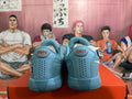 Rear view of blue Nike basketball sneakers showing red tongue details, heel perforations, and textured outsoles.
