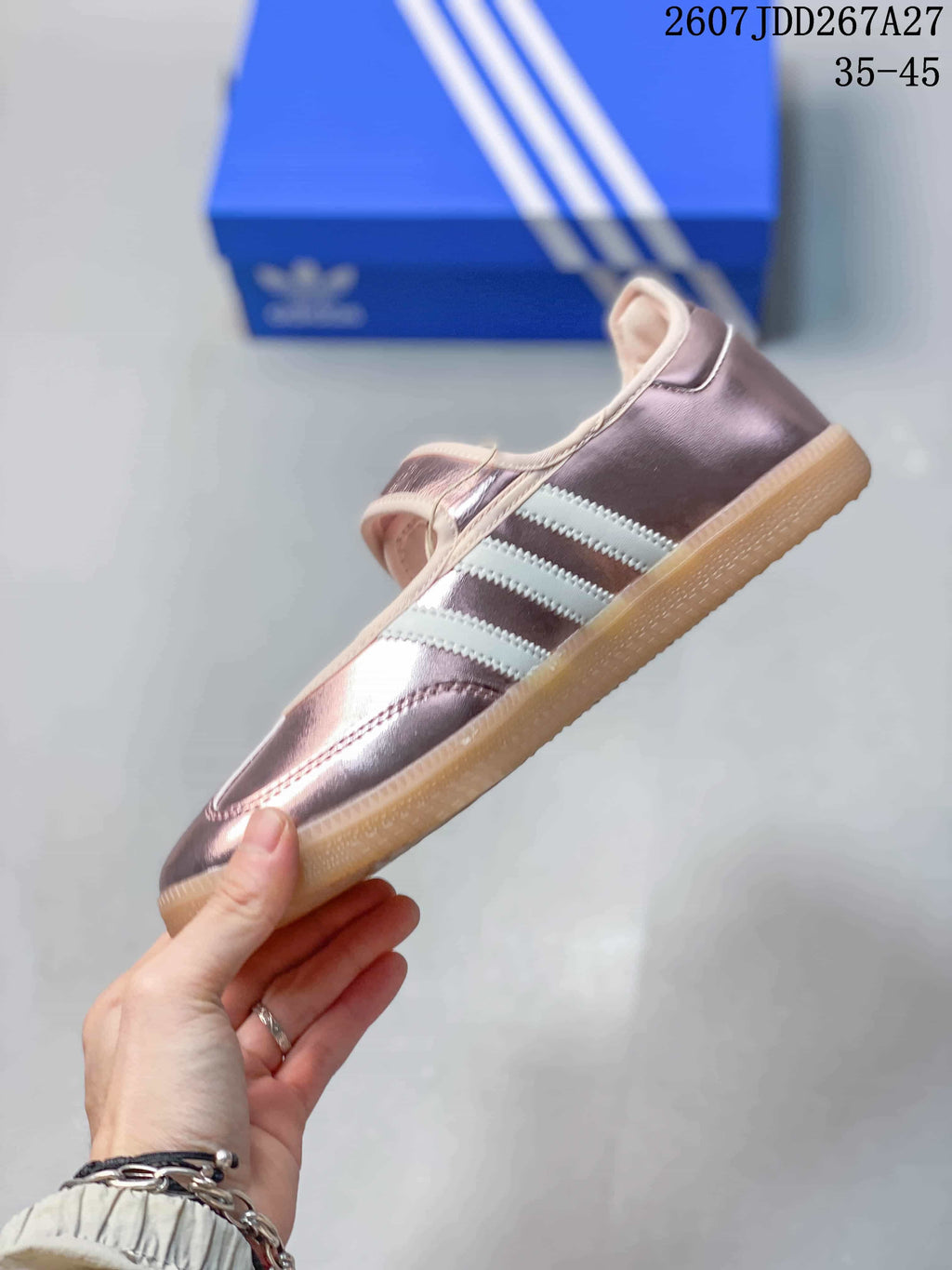 Side profile showing the metallic pink upper, white adidas stripes, Mary Jane strap and gum-colored outsole.