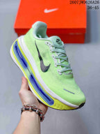 Angled side view of a green Nike sneaker showing the black Swoosh, laces, and layered white, blue, and yellow sole.