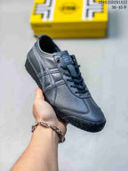 Angled side view of the black sneaker showing the lace-up upper, layered stripes, rounded toe, and textured outsole.