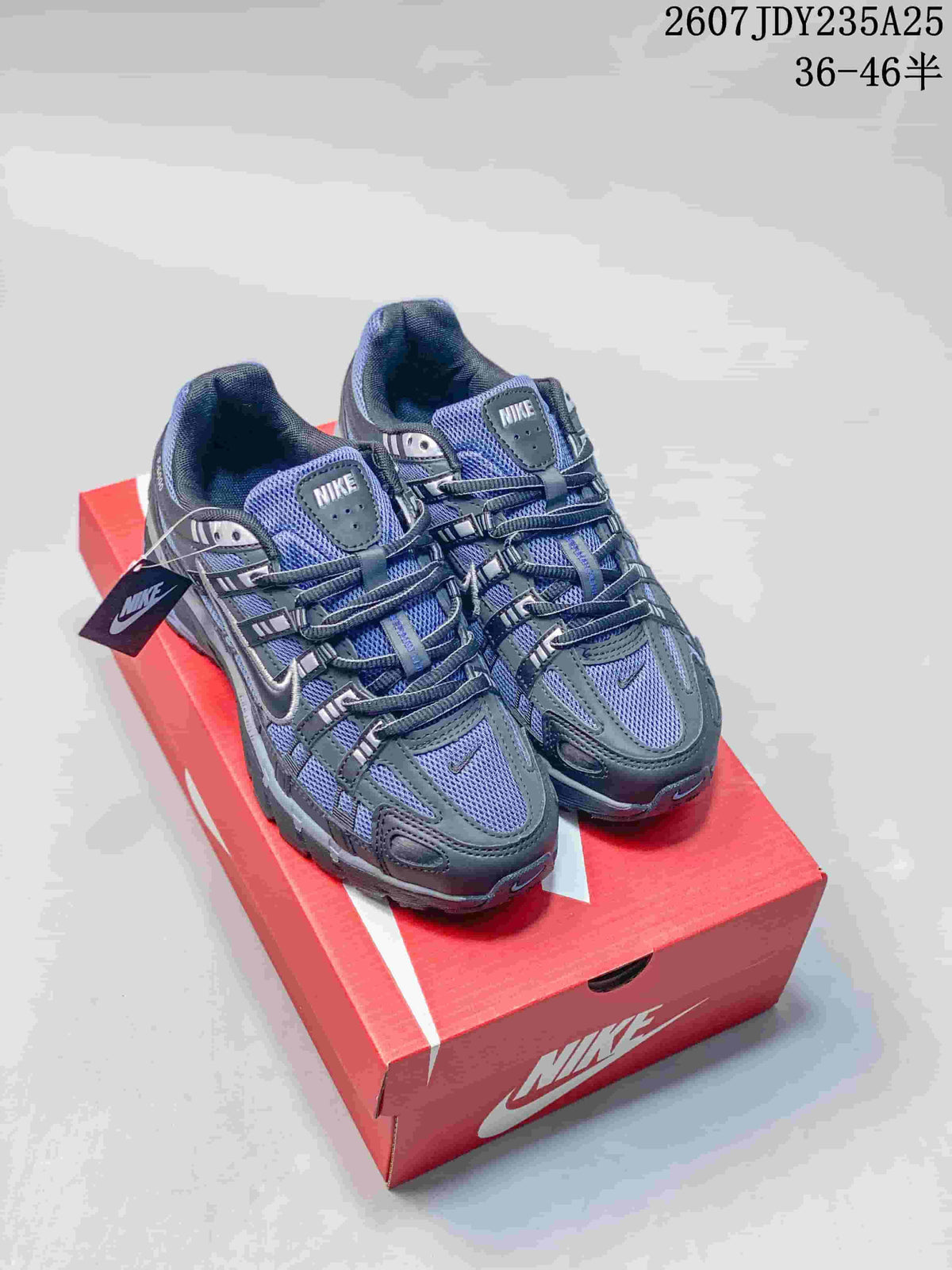 Dark gray and blue-toned Nike P-6000 sneakers displayed on a red shoebox.
