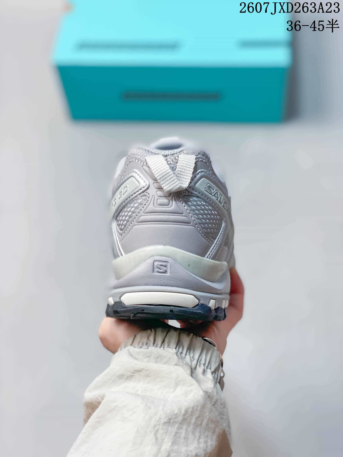 Rear view of the gray and silver sneaker showing the padded heel collar, heel pull tab, layered panels, and lugged outsole.