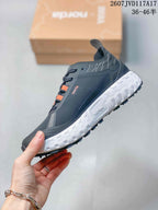 Side profile highlighting the textured upper, lace system, orange accent strip, white midsole, and black outsole.