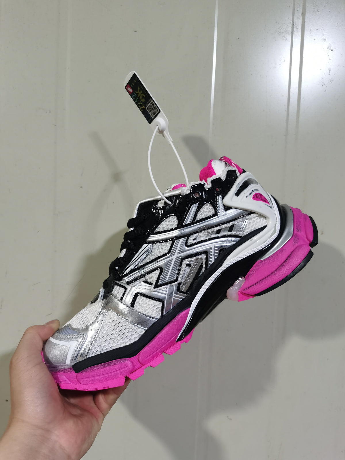 Side view showing the silver and black upper, black laces, fluorescent pink heel and textured outsole.