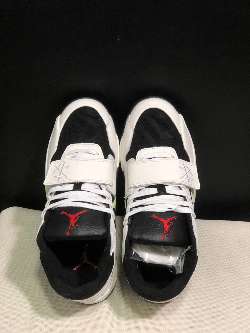 Top view showing white laces, wide midfoot straps, black toe panels, and red tongue branding.