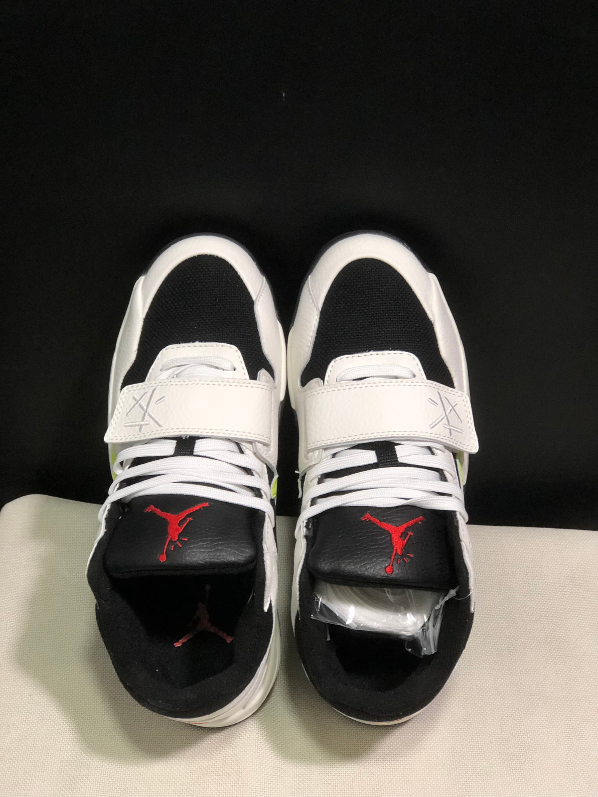 Top view showing white laces, wide midfoot straps, black toe panels, and red tongue branding.