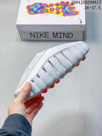 Side profile of the white Nike Mind slide showing the perforated upper, sculpted sidewall and orange outsole elements.
