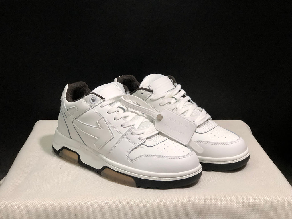 Three-quarter view of the white sneaker pair showing the side panels, laces, toe boxes, and attached tag accessory.
