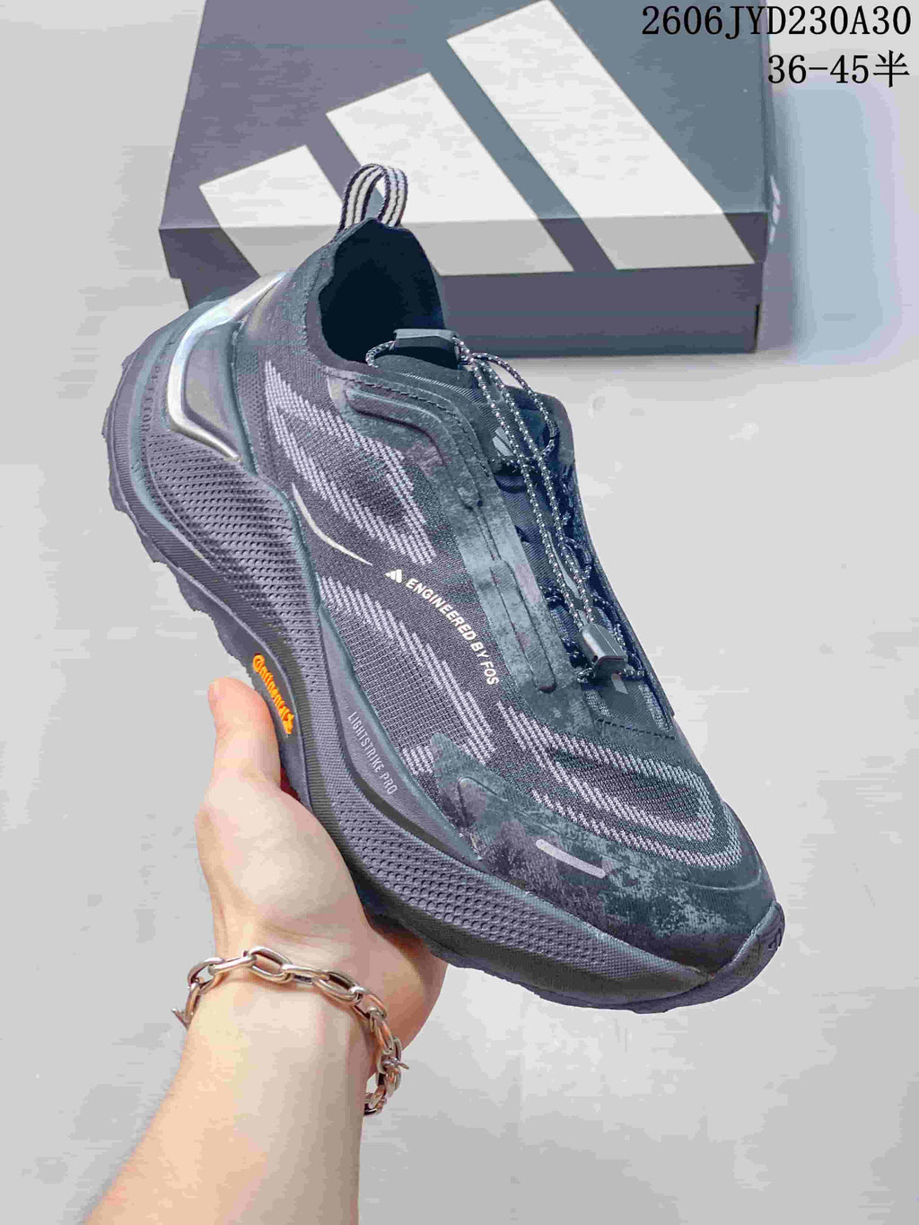 Angled side view of a gray Adidas Holo Peak shoe with patterned upper and lugged outsole
