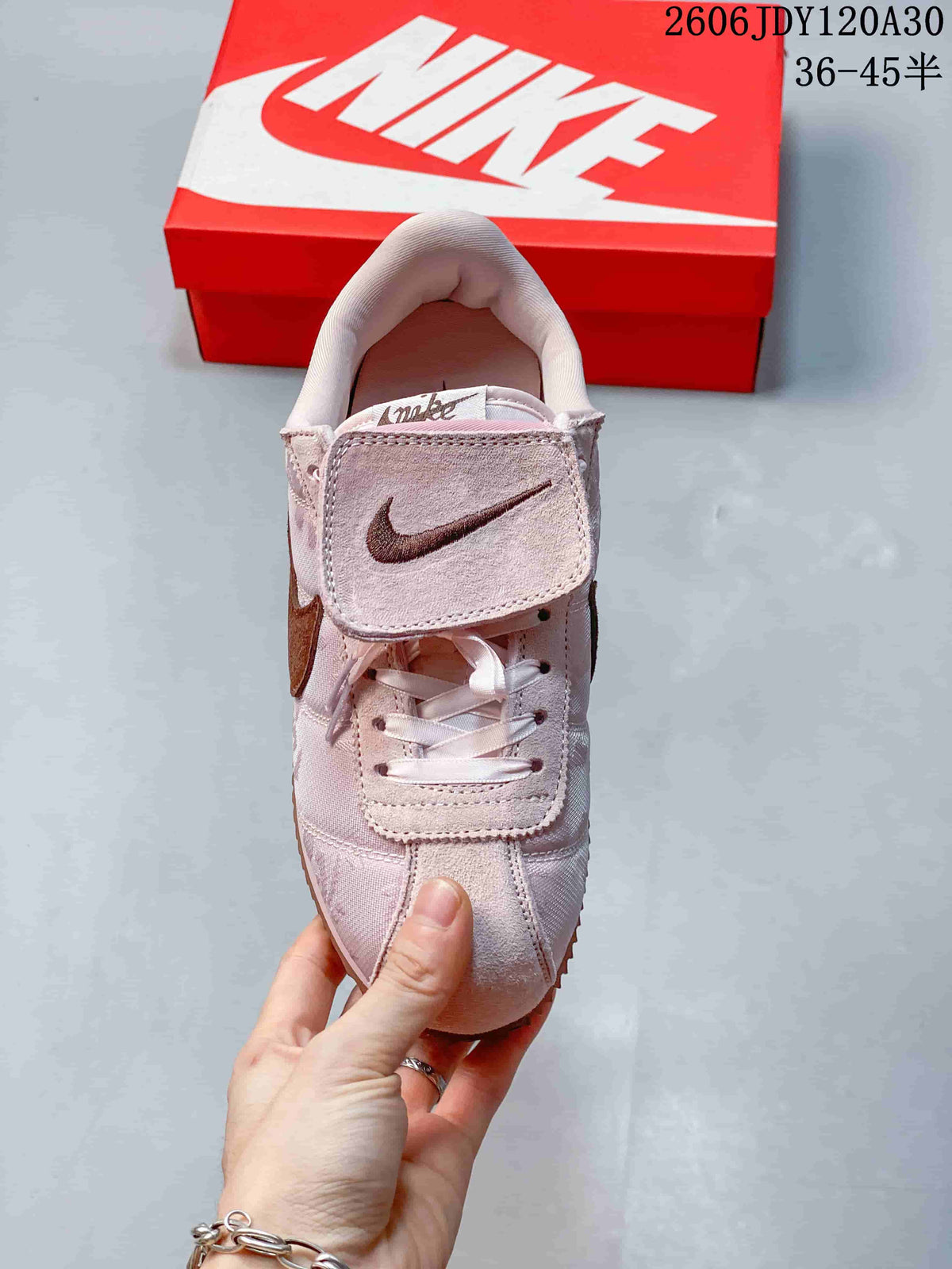 Front view of a pale pink Nike Classic Cortez sneaker showing its laces and fold-over tongue flap