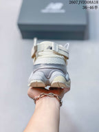 Rear view of a white and light gray New Balance 9060 sneaker showing the layered heel and padded collar.