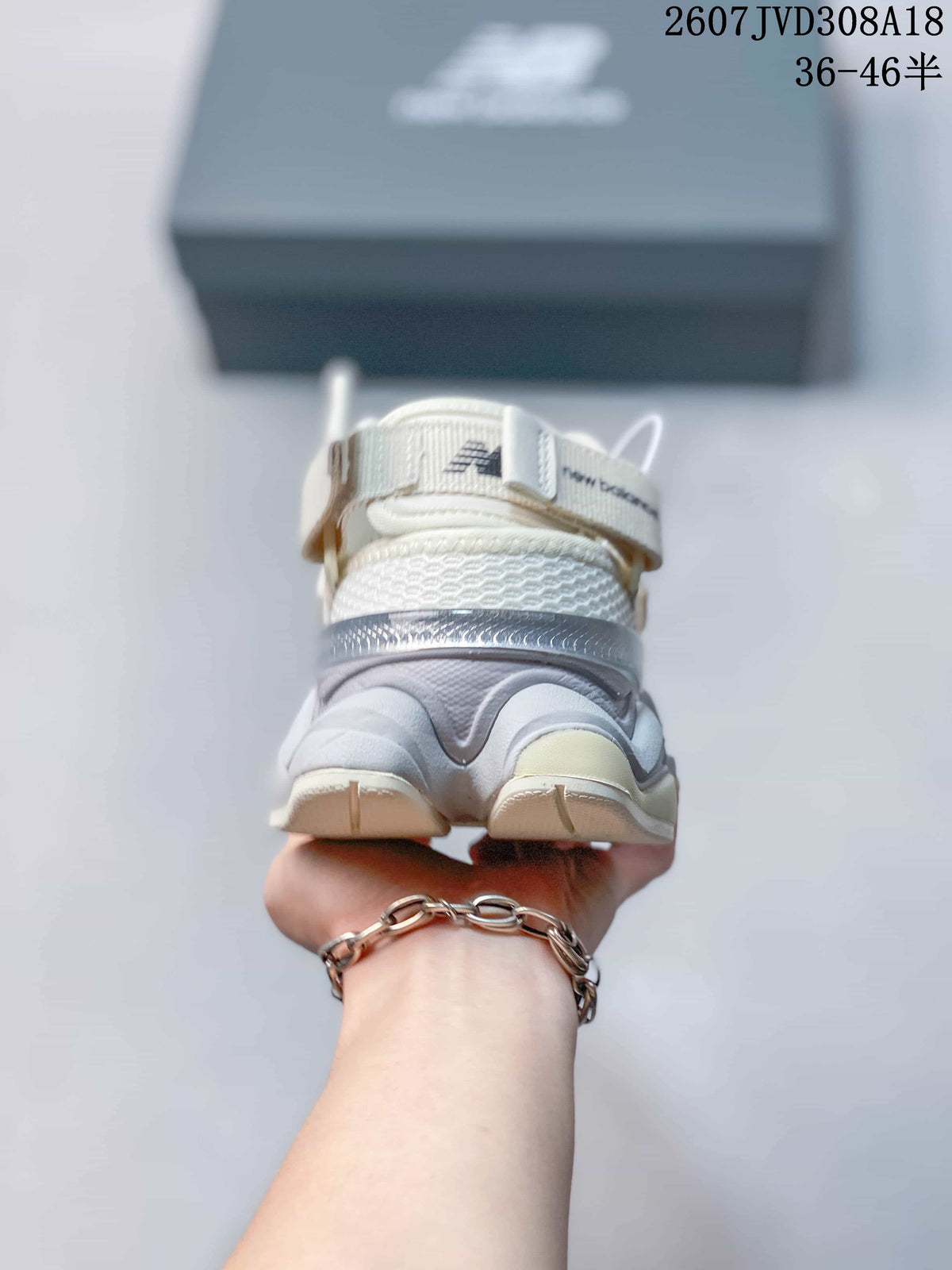 Rear view of a white and light gray New Balance 9060 sneaker showing the layered heel and padded collar.