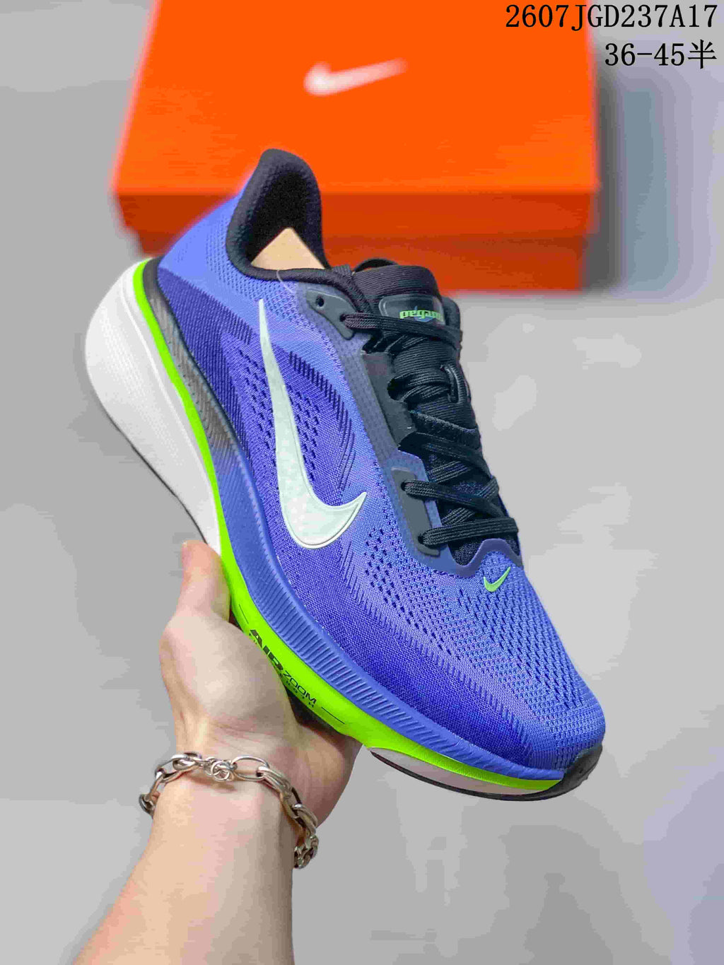Angled side view of a purple and blue Nike Air Zoom Pegasus 42 shoe with a white Swoosh, black laces, and layered white and bright green sole.