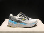 Side profile of one Brooks Glycerin 21 shoe against a dark background, showing its white and grey colorway, black laces, blue midsole accent, and yellow outsole details.