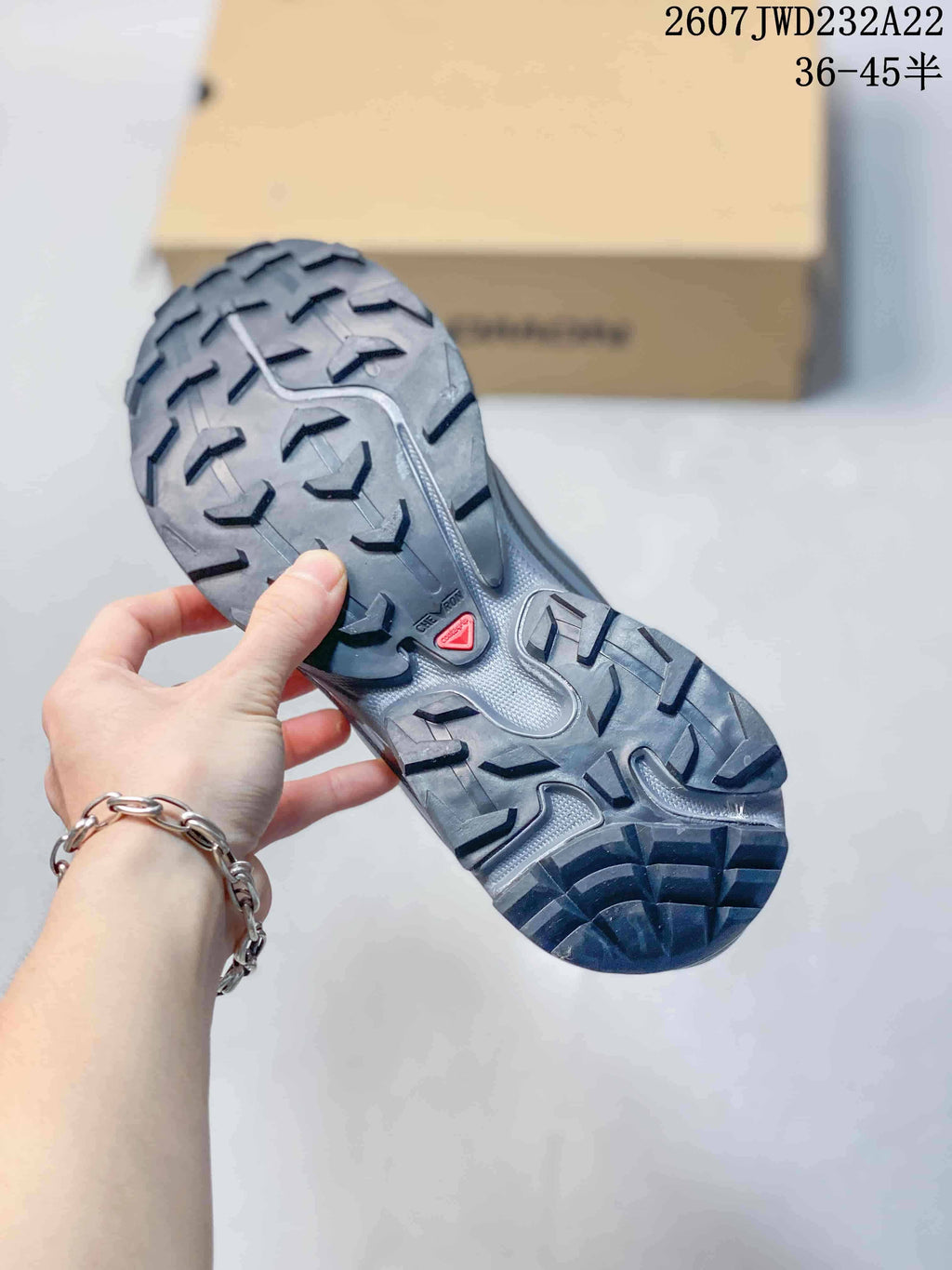 Close view of the sneaker outsole showing a rugged gray and black multidirectional lug pattern.