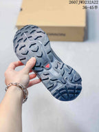 Close view of the sneaker outsole showing a rugged gray and black multidirectional lug pattern.