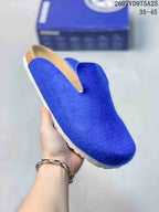 Angled close view of a blue closed-toe slip-on clog with a tan footbed area and white outsole.