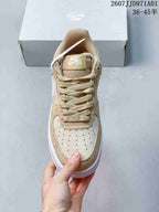 Front view showing the perforated toe and laces of a beige and white Nike Air Force 1 '07 sneaker