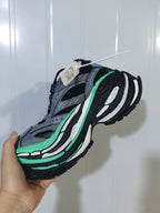 Side view of the grey and green mesh sneaker showing layered panels, blue accents and a chunky outsole.