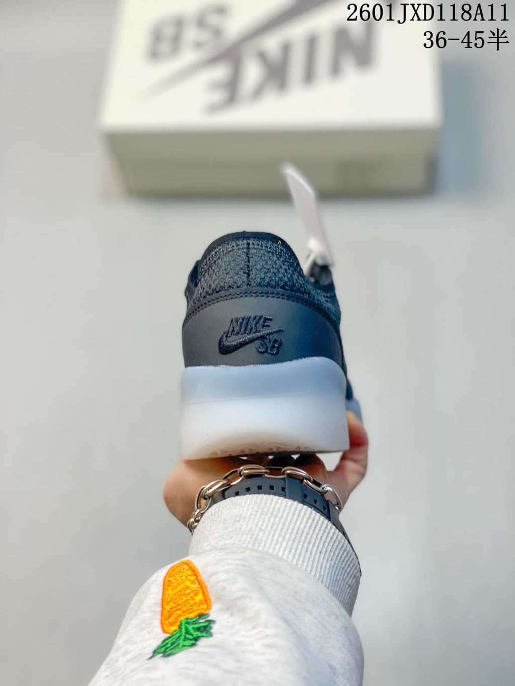 Rear view of a dark gray Nike SB shoe showing the branded heel panel and translucent midsole.