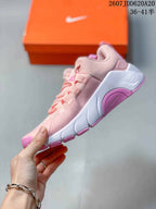 Side view of the pink and white training shoe showing the mesh-style upper, layered lacing, sculpted white midsole, and pink outsole sections.