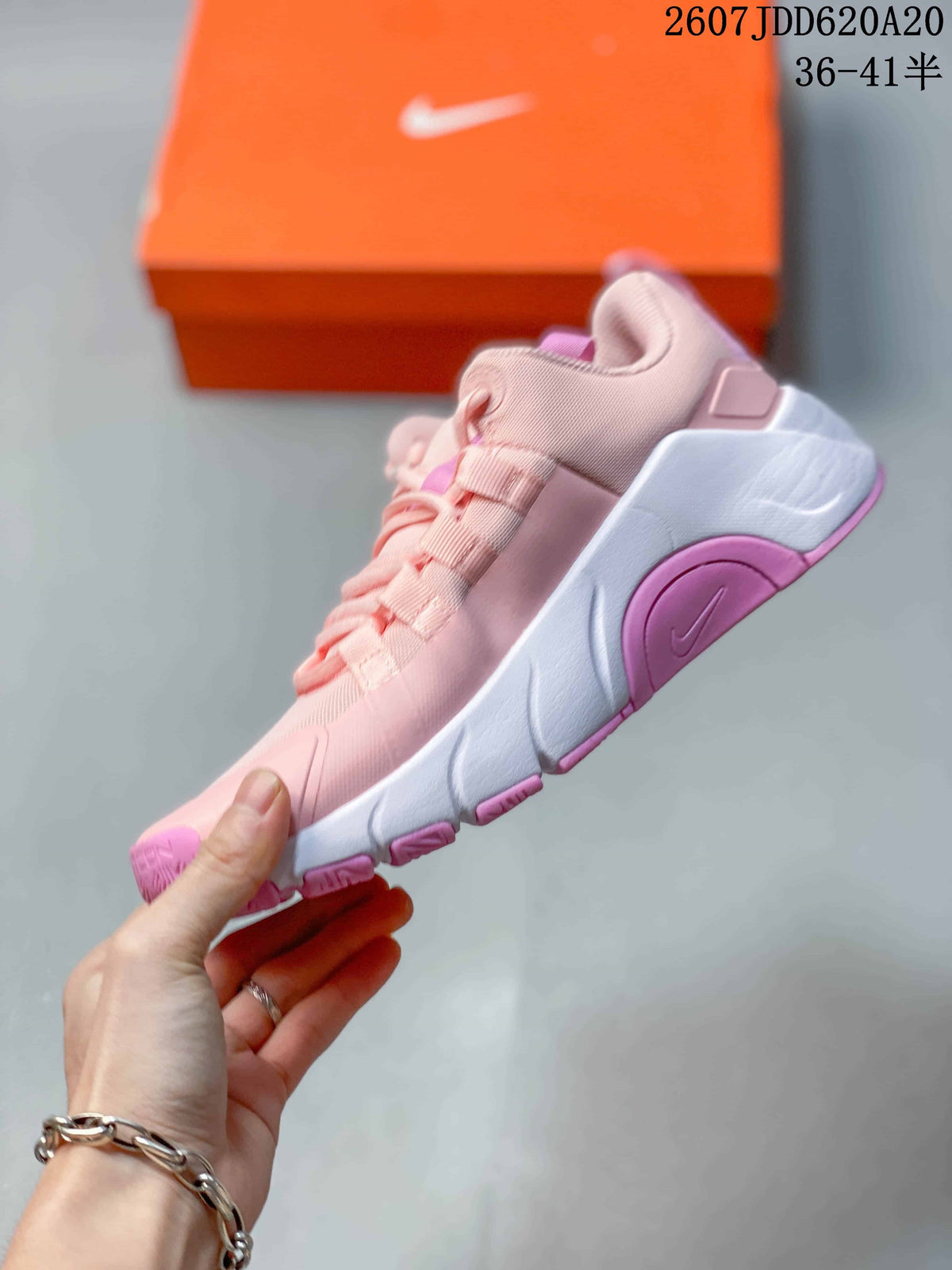 Side view of the pink and white training shoe showing the mesh-style upper, layered lacing, sculpted white midsole, and pink outsole sections.