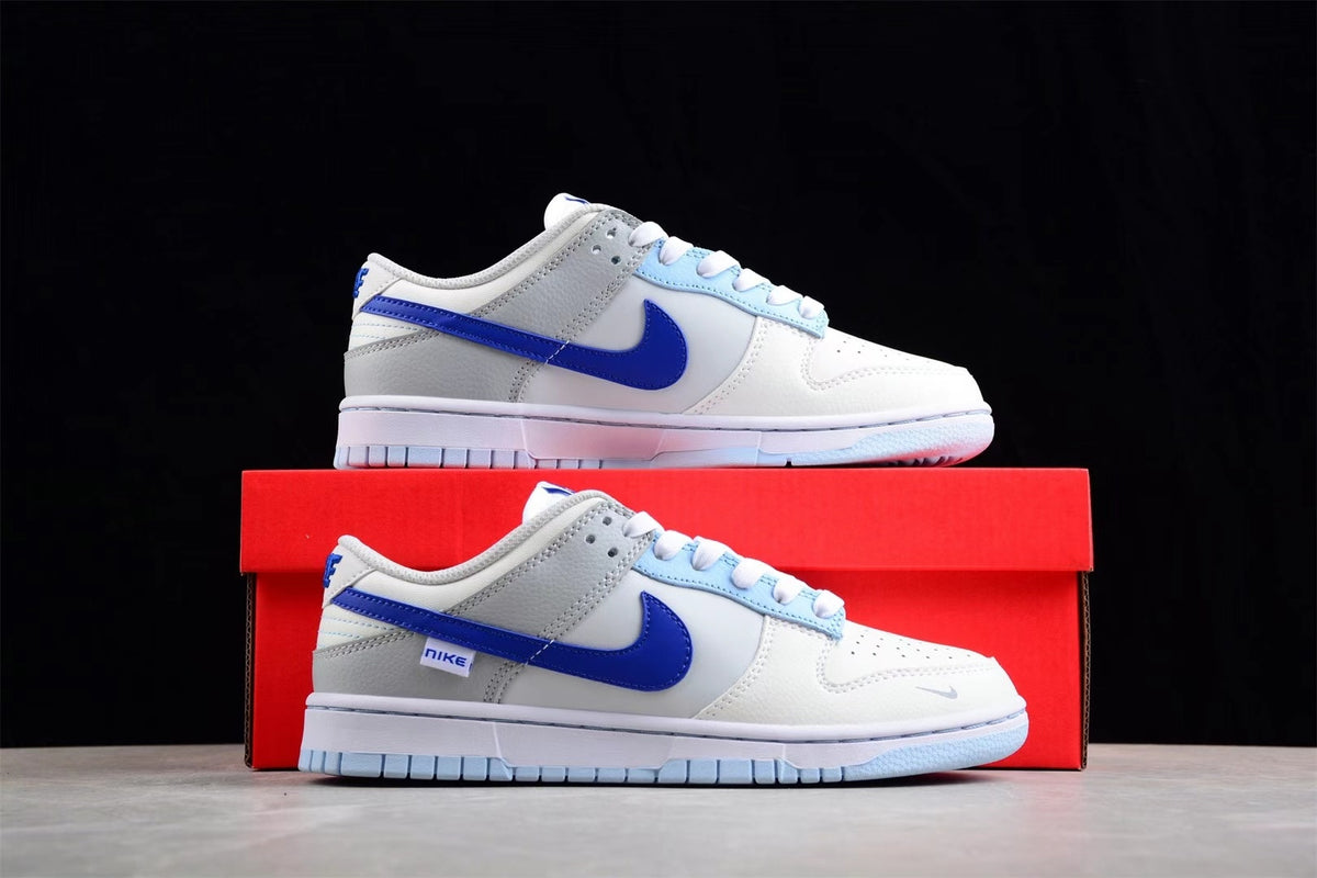 Side view of white and blue Nike SB low-top sneakers displayed on a red shoebox.