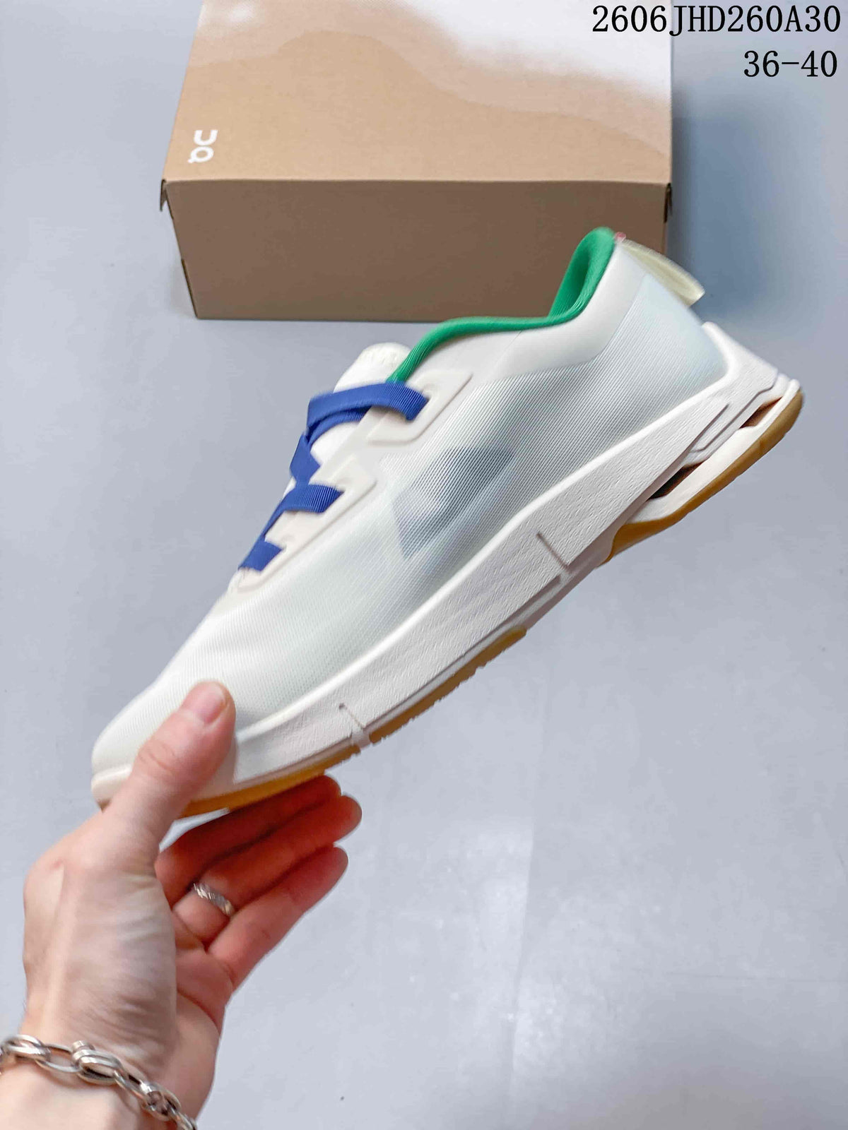 Side view of the white sneaker with blue lacing and a gum-colored outsole