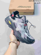 Angled side view of the silver and black Mizuno sneaker with its layered upper and textured outsole.