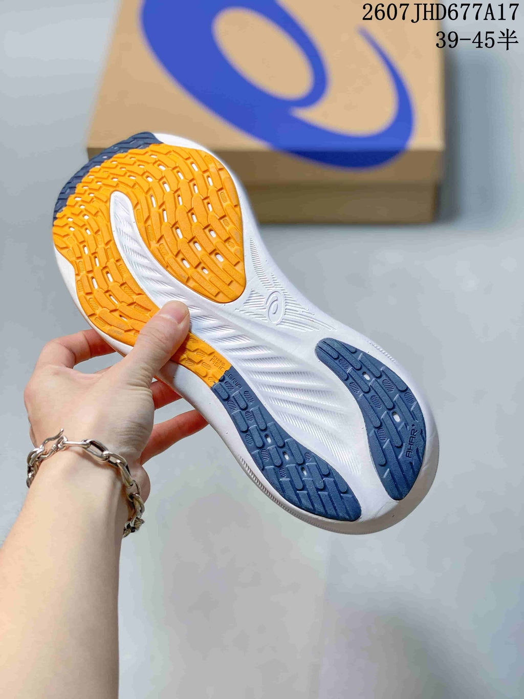 Close-up of the sneaker outsole showing orange and dark blue rubber traction sections with a white midsole.