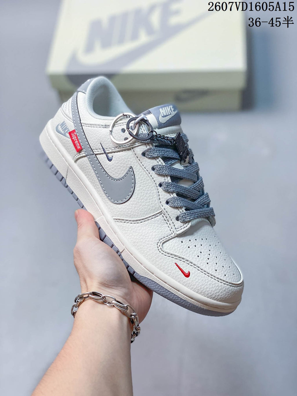 Angled side view showing the gray Swoosh, red toe accent, side tag, and decorative attachments.