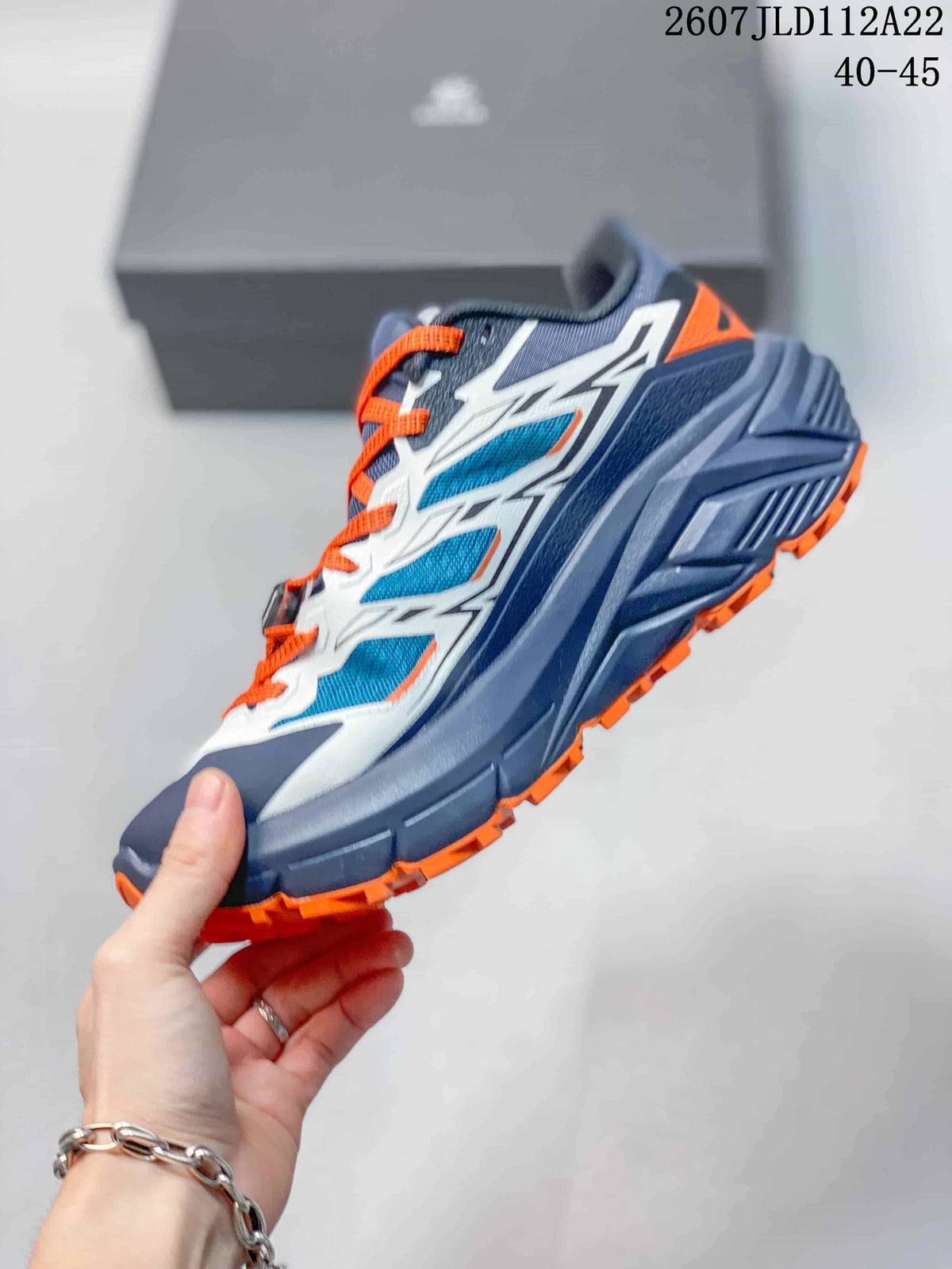Side view of the Kailas C4 sneaker showing the mesh-panel upper, white overlays, sculpted navy midsole, and orange outsole lugs.