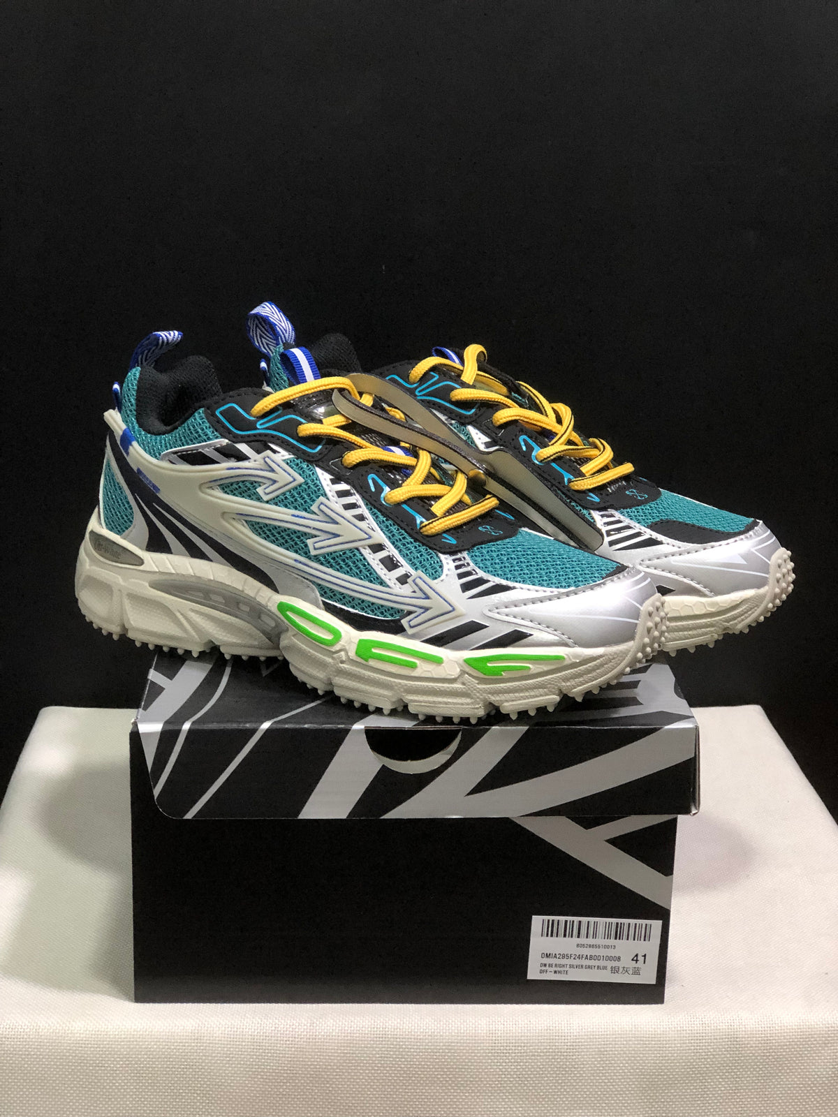 Pair of teal, white, black, and yellow Off-White Be Right Back sneakers displayed on a branded shoebox.