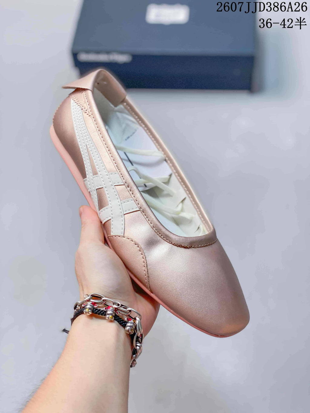 Angled close-up of the pink metallic shoe showing the rounded toe, white side stripes, and flat outsole.