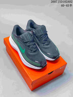 Charcoal Nike-branded low-top running shoes with teal accents on an orange shoebox