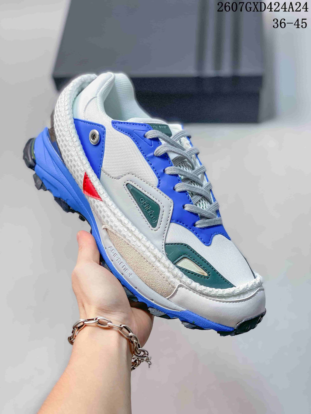 Close-up of a white, blue, gray, and red OZWEEGO sneaker with layered side panels and a textured sole.