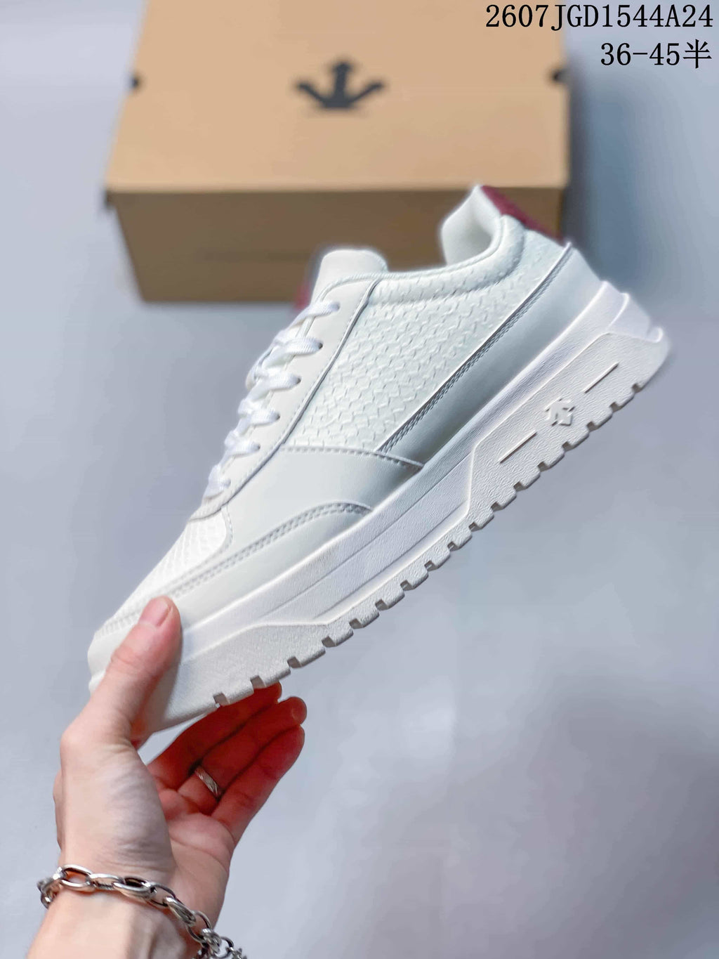 Side view of the white low-top sneaker showing textured panels, layered construction and a patterned outsole.