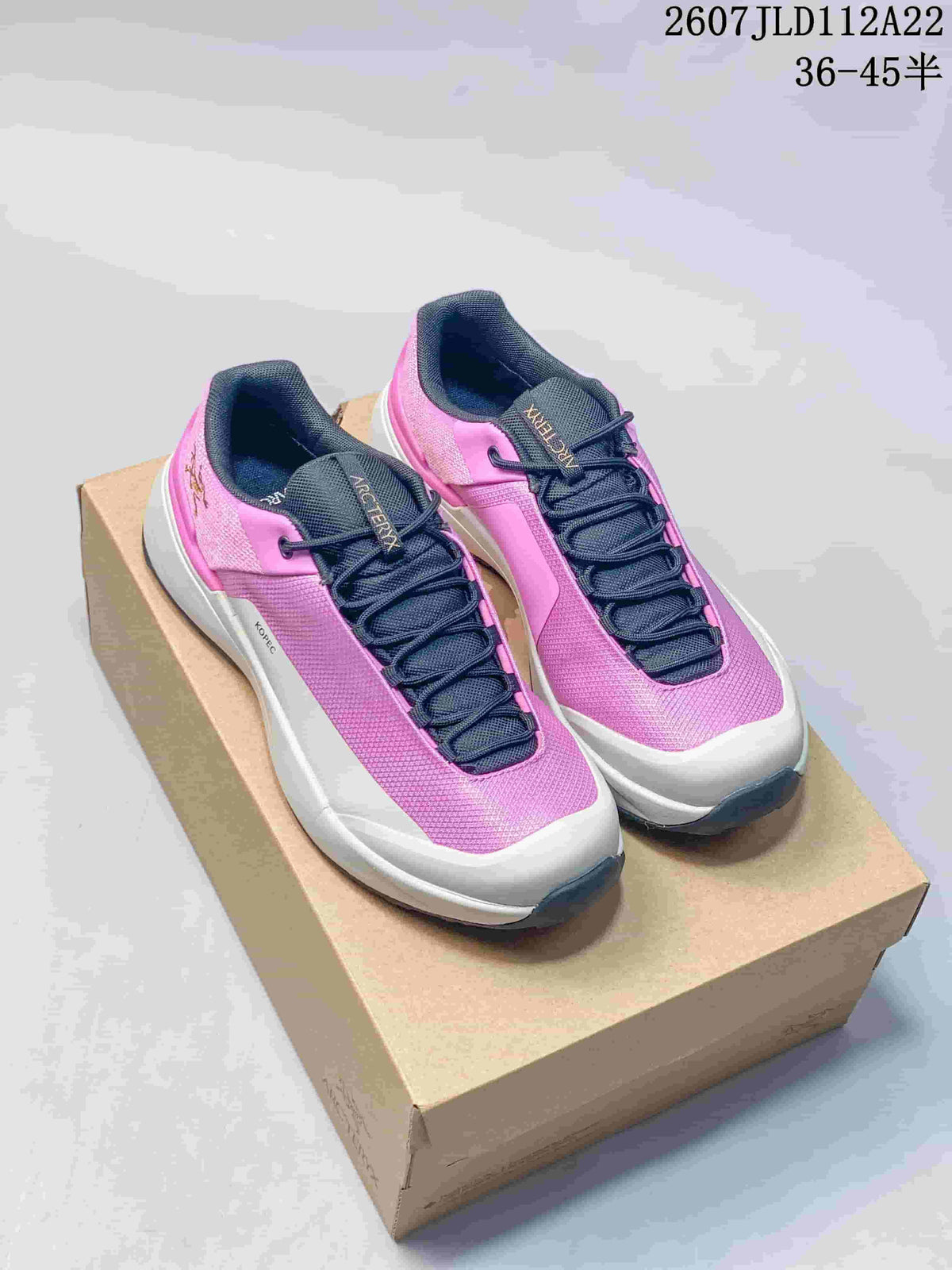 Pair of pink and navy Arc'teryx KOPEC low hiking shoes displayed on a cardboard box; the image also shows the source size range 36–45.5 and code 2607JLD112A22.