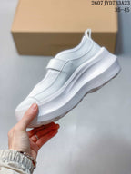 Side view of the white Mary Jane-style sneaker showing the strap and layered platform sole.