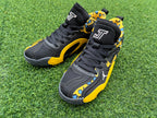 Close-up front view of black lace-up sneakers with yellow leopard-print panels