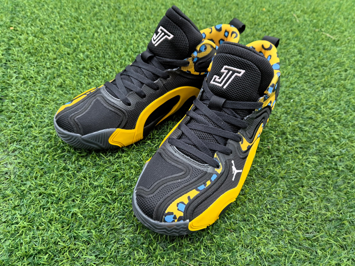 Close-up front view of black lace-up sneakers with yellow leopard-print panels