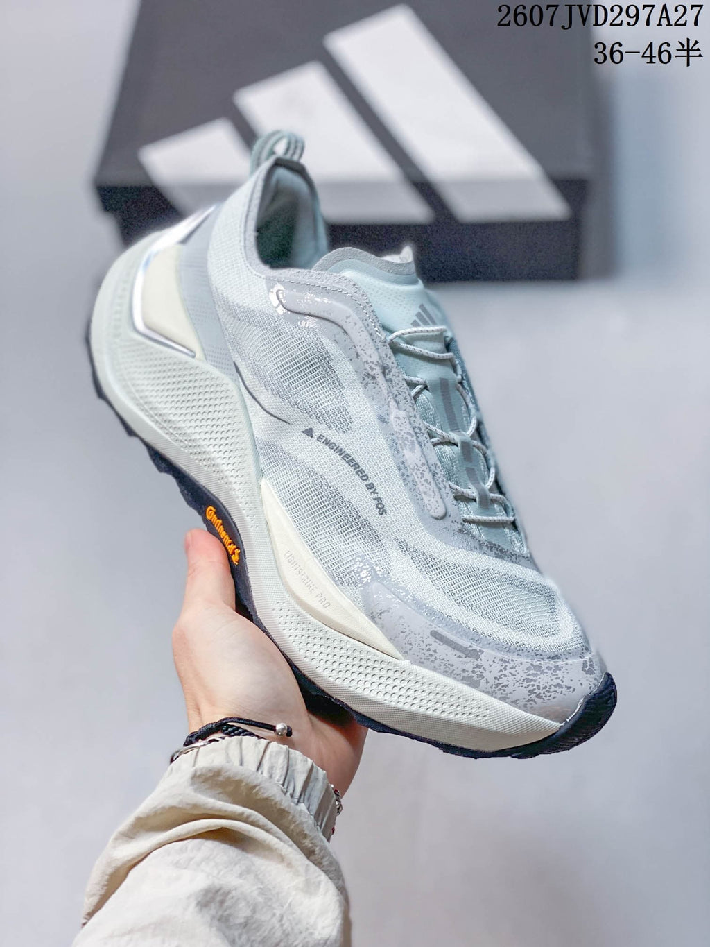 Three-quarter side view showing the light gray mesh-like upper, overlays, pull tab, and contrasting outsole.