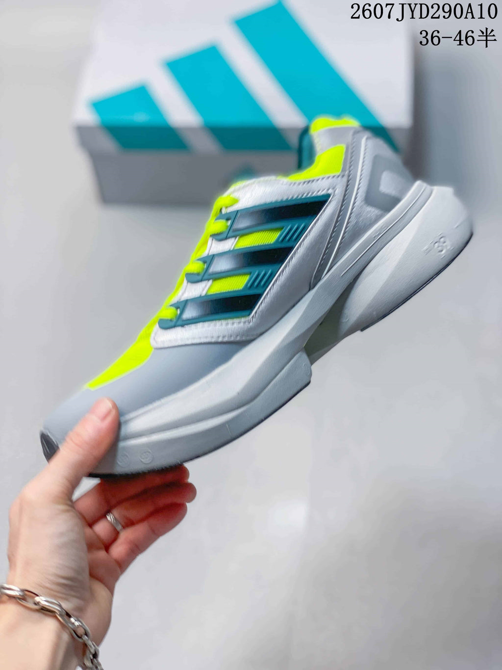 Side view of the adidas Equipment Adios Pro running shoe showing layered grey and teal side panels, neon yellow details and a sculpted sole.
